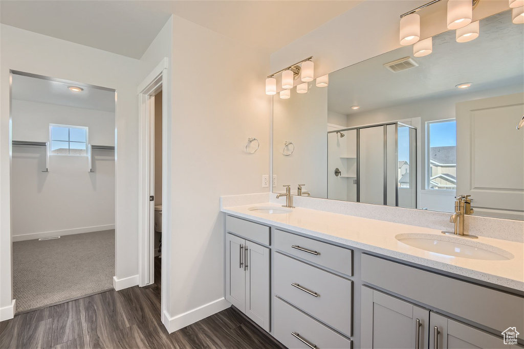 Bathroom featuring toilet, hardwood / wood-style floors, a shower with door, dual sinks, and oversized vanity