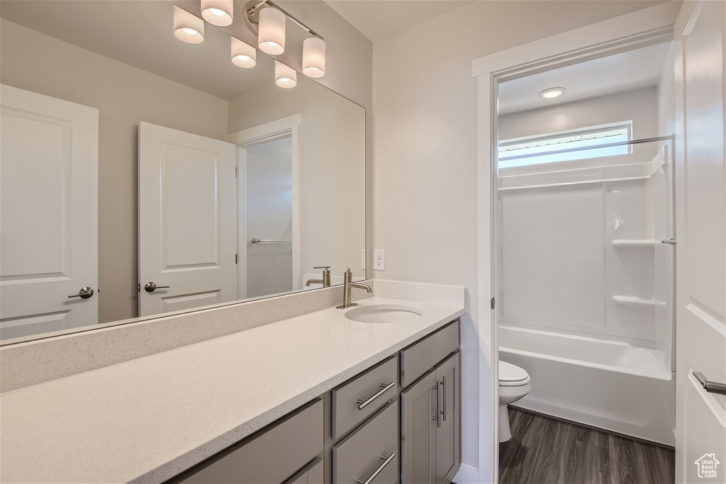 Full bathroom featuring hardwood / wood-style flooring, large vanity, toilet, and tub / shower combination