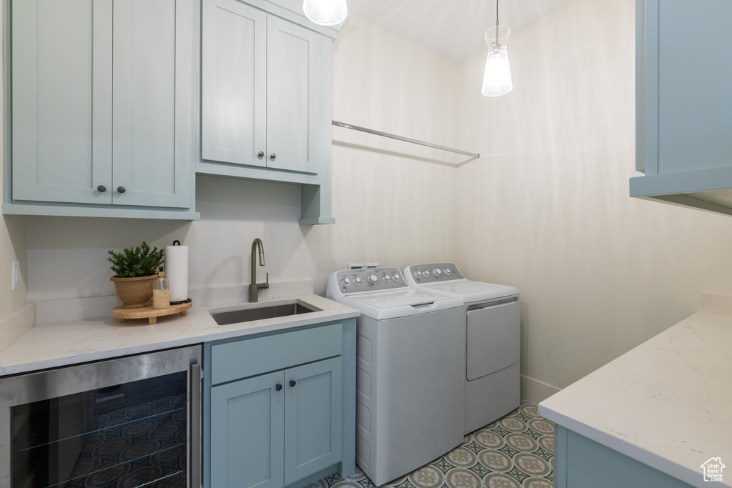 Laundry room featuring dark tile flooring, cabinets, beverage cooler, sink, and washing machine and clothes dryer