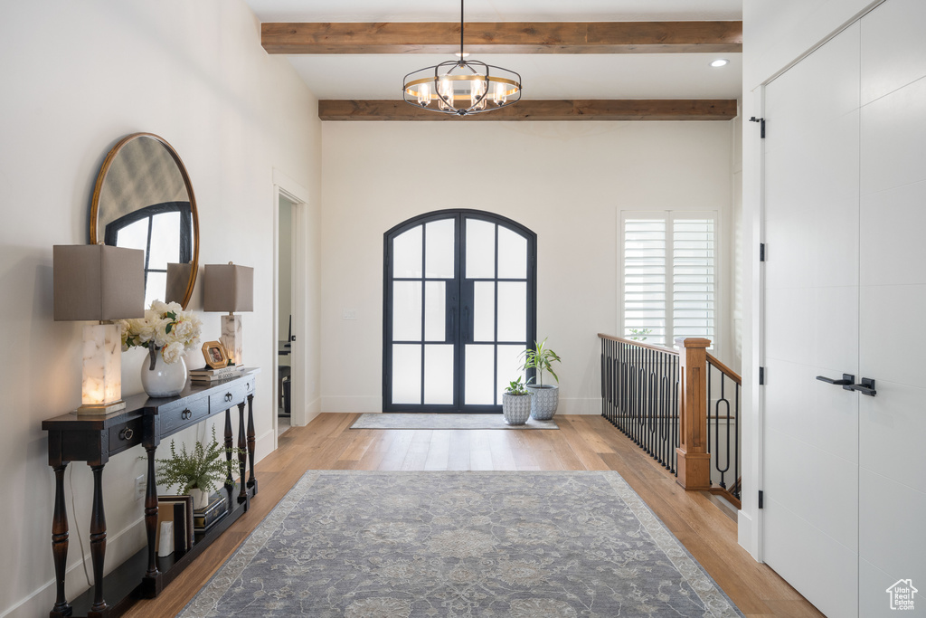 Foyer entrance with light hardwood / wood-style flooring, beam ceiling, and a chandelier