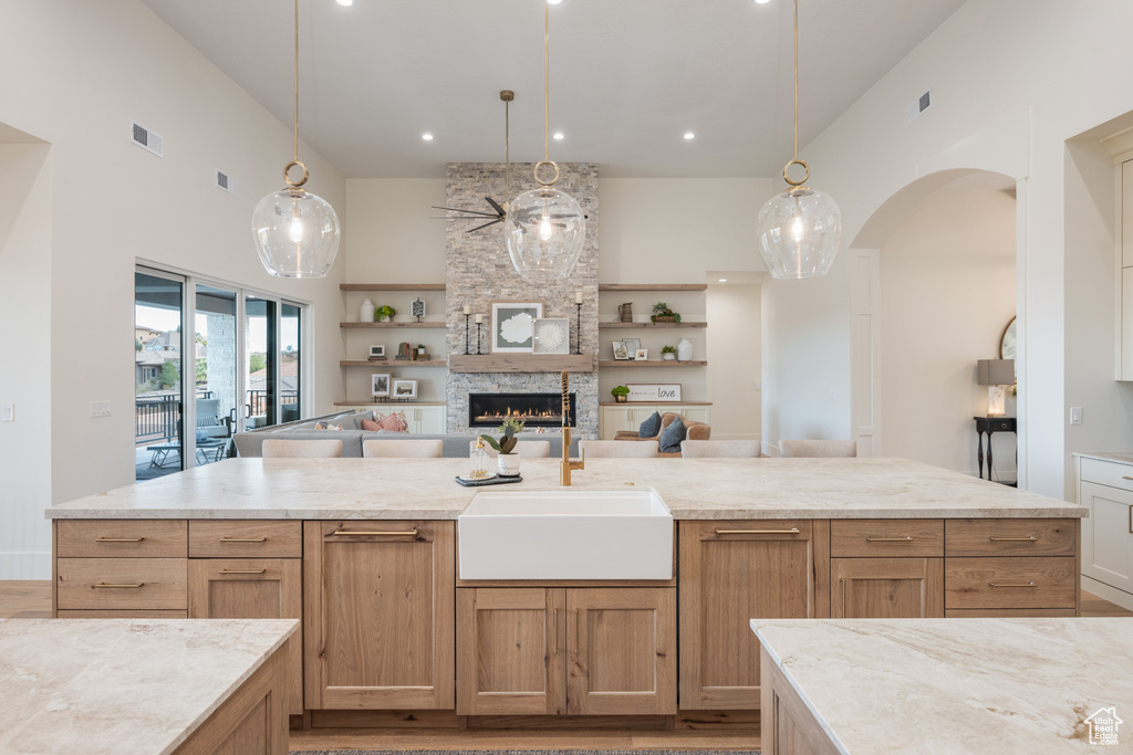 Kitchen with pendant lighting, sink, a towering ceiling, and a stone fireplace