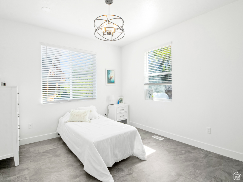 Bedroom with a notable chandelier, light tile floors, and multiple windows