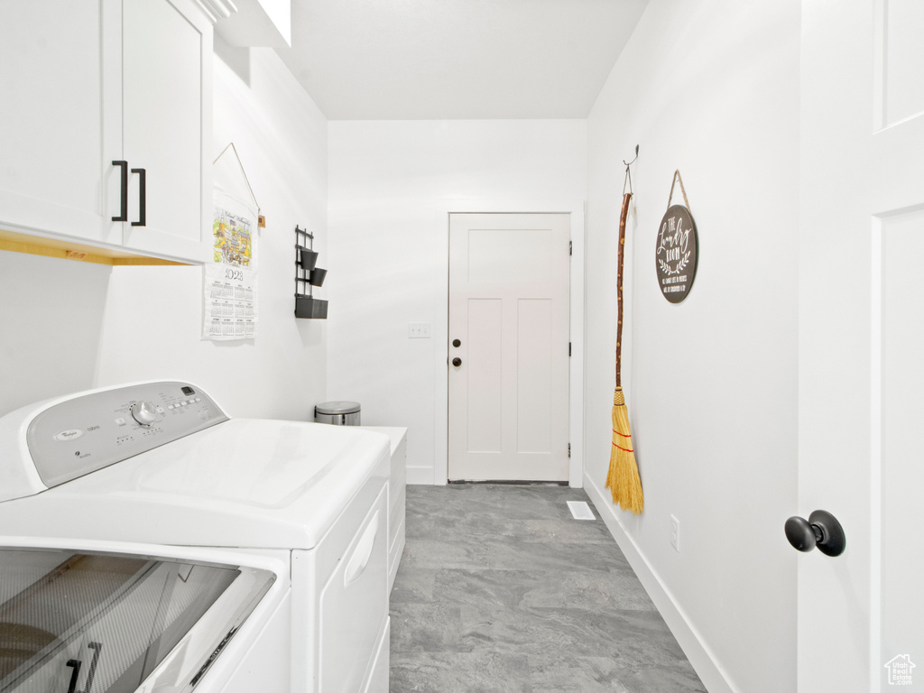 Clothes washing area with cabinets, light tile floors, and independent washer and dryer