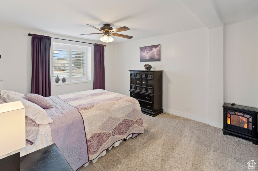 Carpeted bedroom with ceiling fan and a wood stove