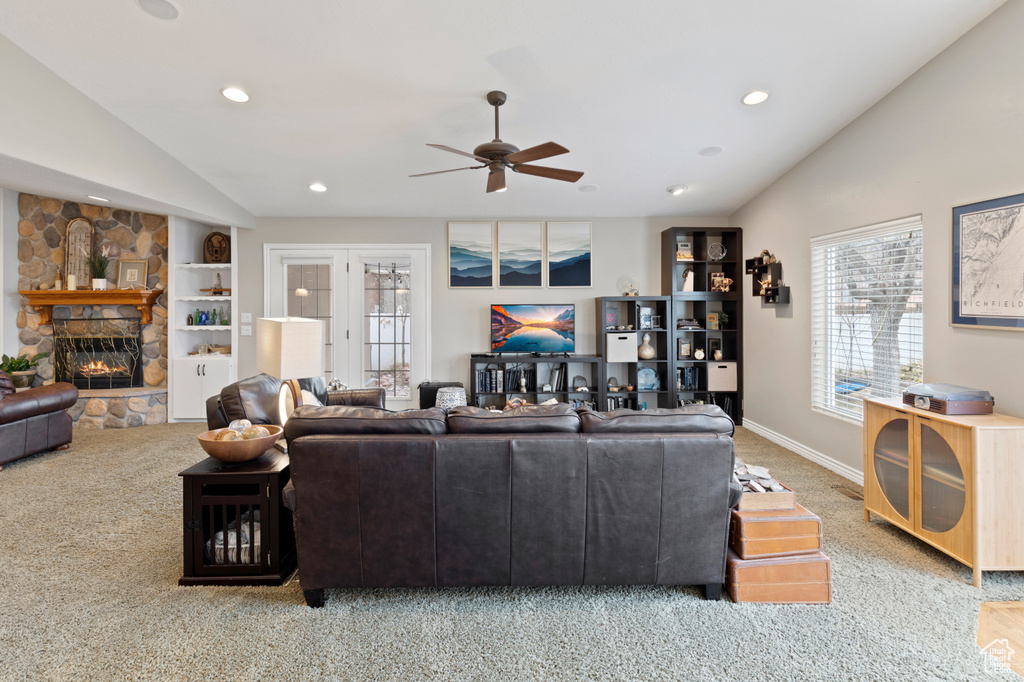 Living room featuring a fireplace, lofted ceiling, ceiling fan, and light colored carpet
