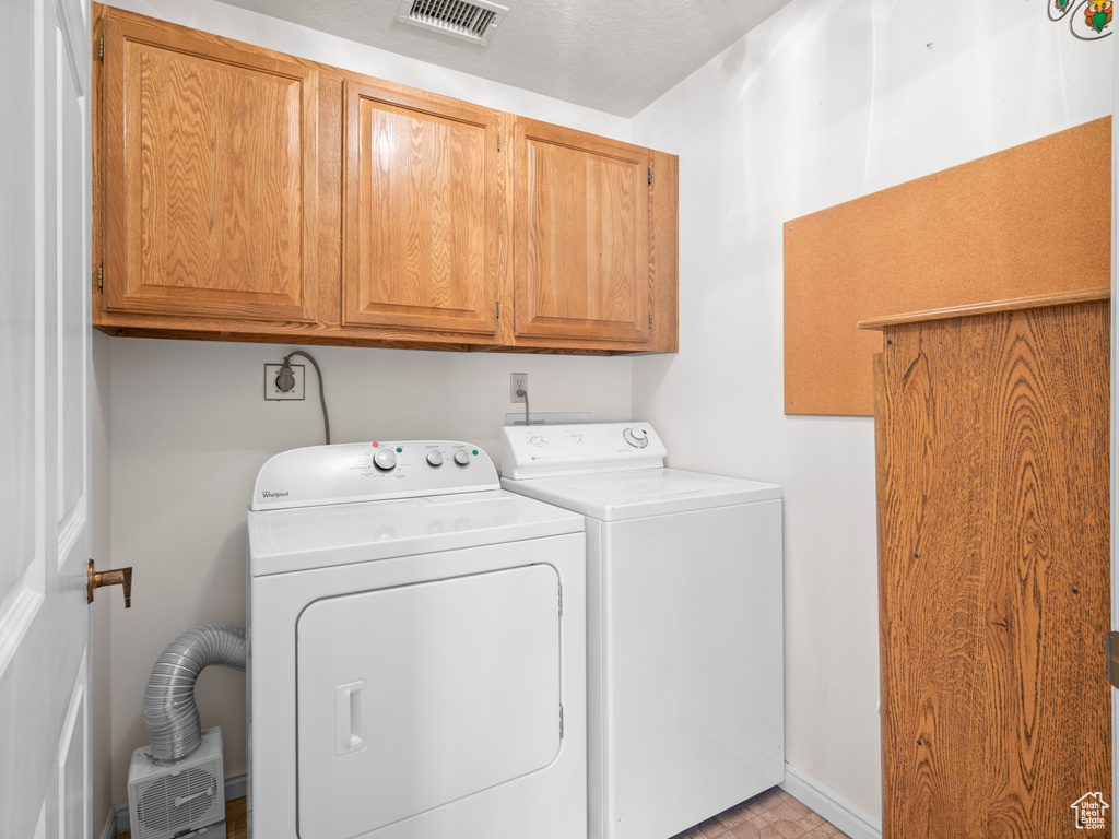 Clothes washing area featuring cabinets, washing machine and clothes dryer, and hookup for an electric dryer