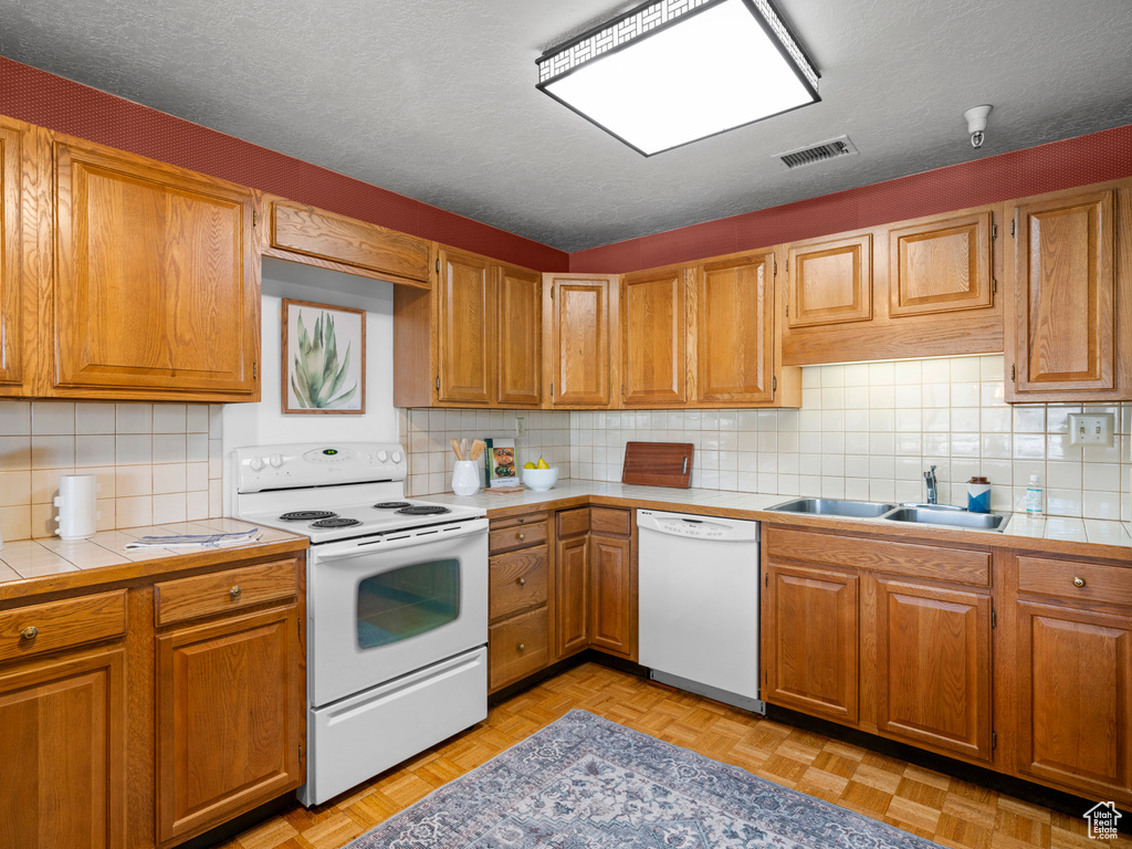 Kitchen featuring tasteful backsplash, light parquet floors, white appliances, and a textured ceiling