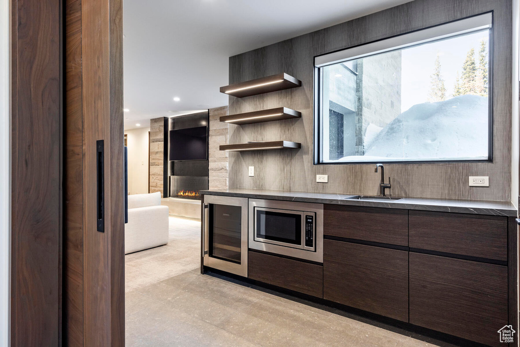 Kitchen featuring sink, a fireplace, stainless steel microwave, and beverage cooler