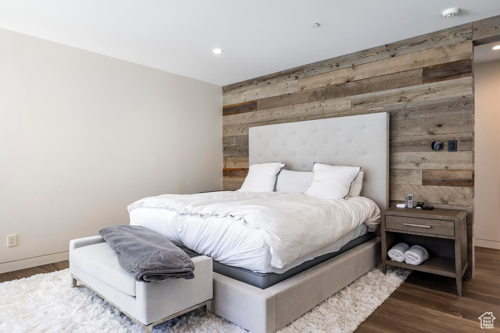 Bedroom with wood walls and dark hardwood / wood-style floors