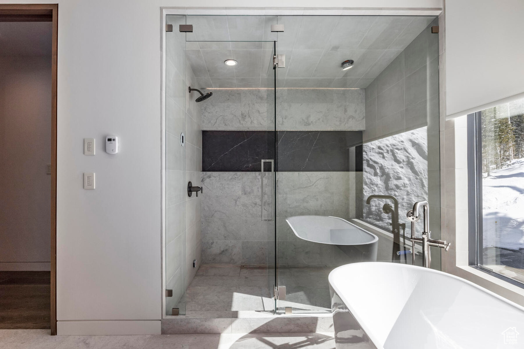 Bathroom featuring independent shower and bath and tile walls