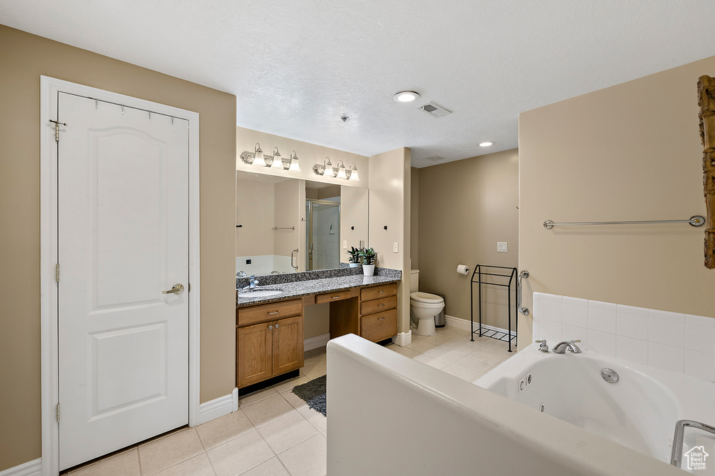 Bathroom with toilet, tile floors, a bath, and vanity with extensive cabinet space