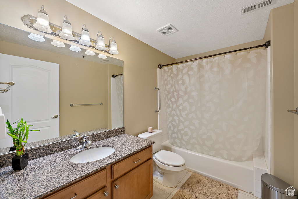 Full bathroom with a textured ceiling, vanity, shower / bath combo, toilet, and tile flooring