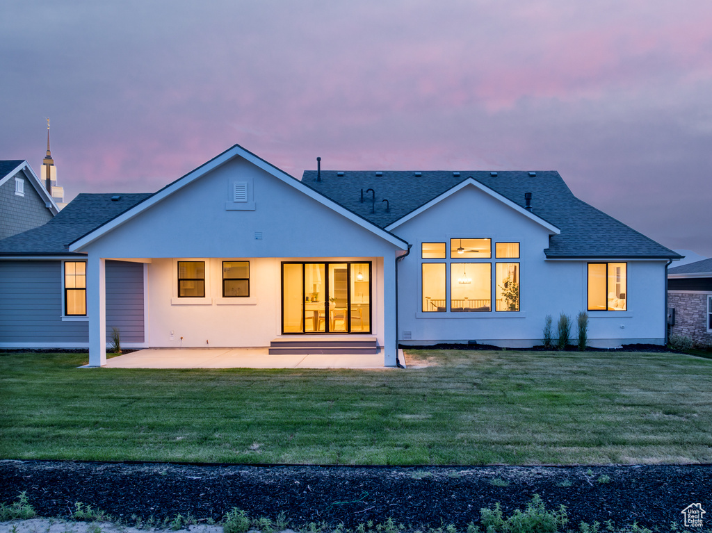 Back house at dusk with a patio area and a yard