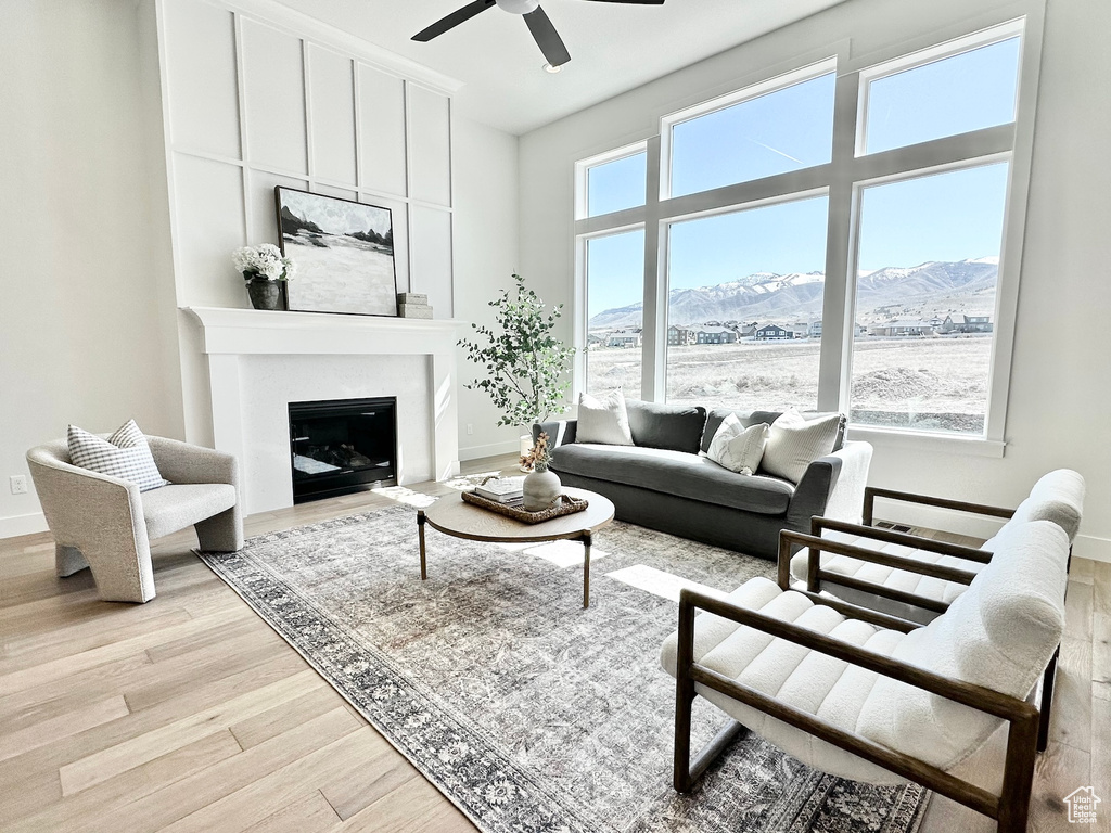 Living room featuring ceiling fan, light hardwood / wood-style flooring, a mountain view, and a towering ceiling