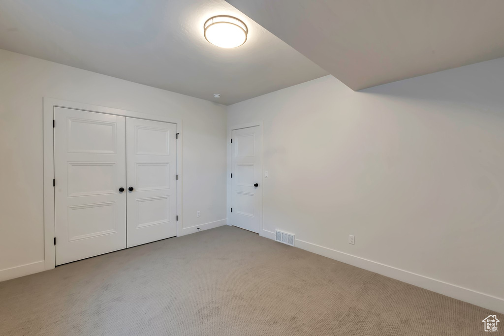 Unfurnished bedroom with light carpet and a closet