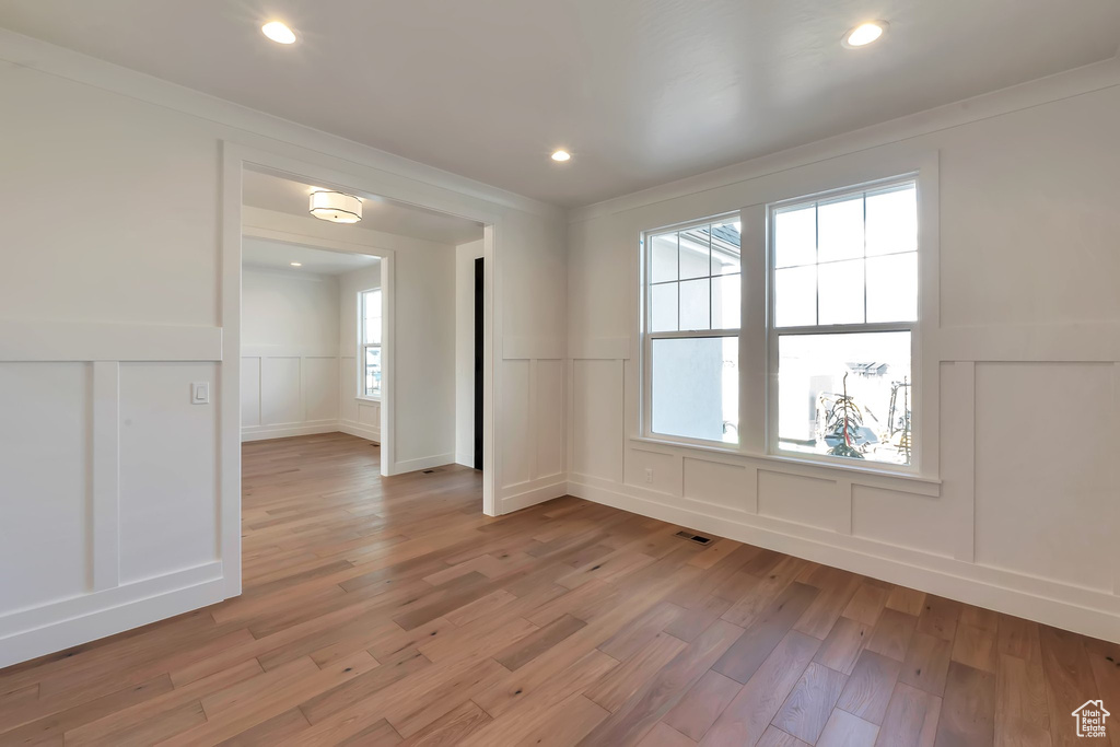 Unfurnished room with light hardwood / wood-style flooring, ornamental molding, and a healthy amount of sunlight