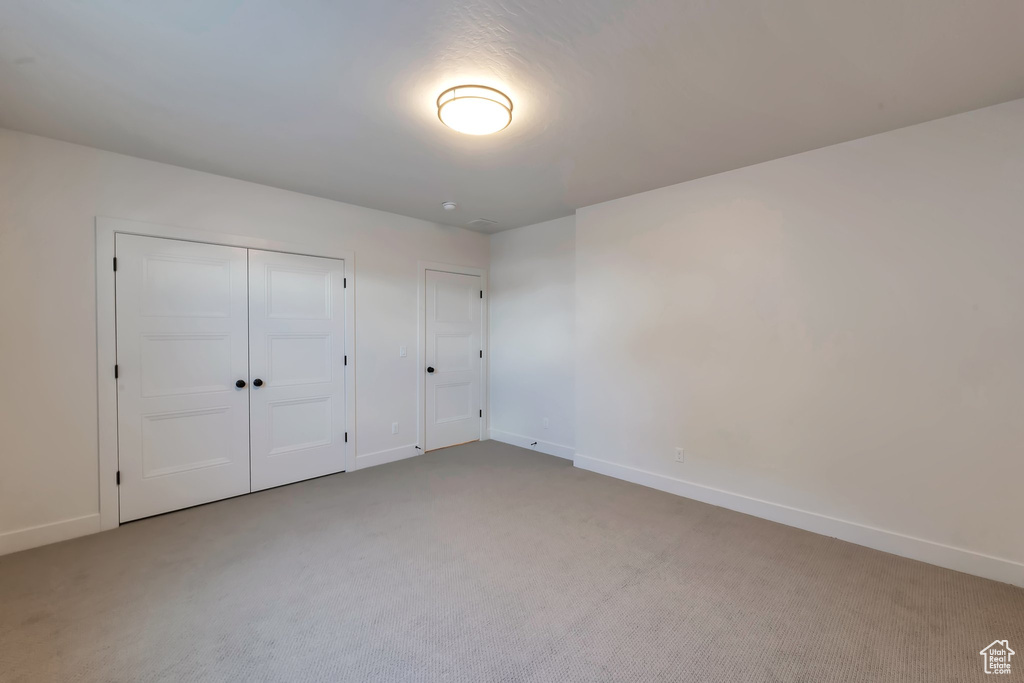 Unfurnished bedroom featuring a closet and light colored carpet