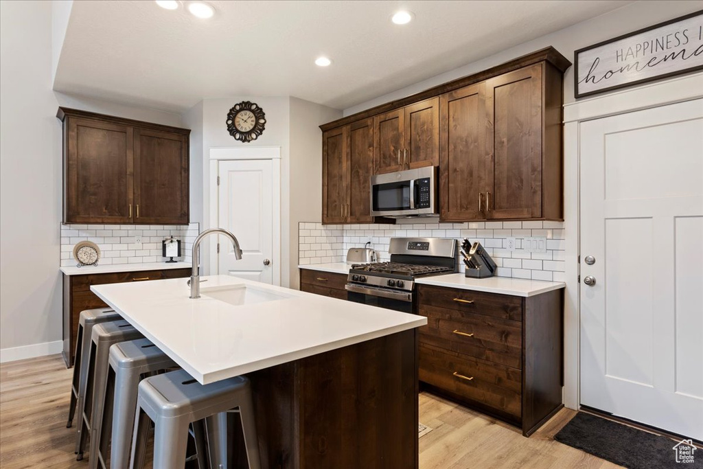 Kitchen with tasteful backsplash, light hardwood / wood-style floors, sink, and stainless steel appliances