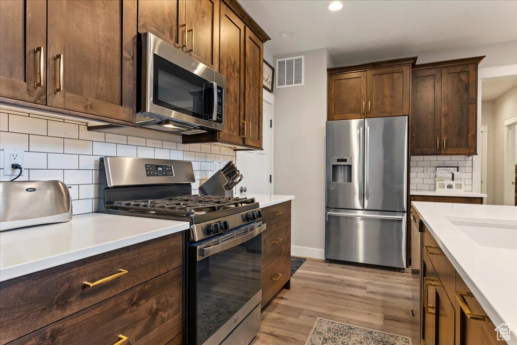 Kitchen featuring light hardwood / wood-style flooring, stainless steel appliances, and tasteful backsplash