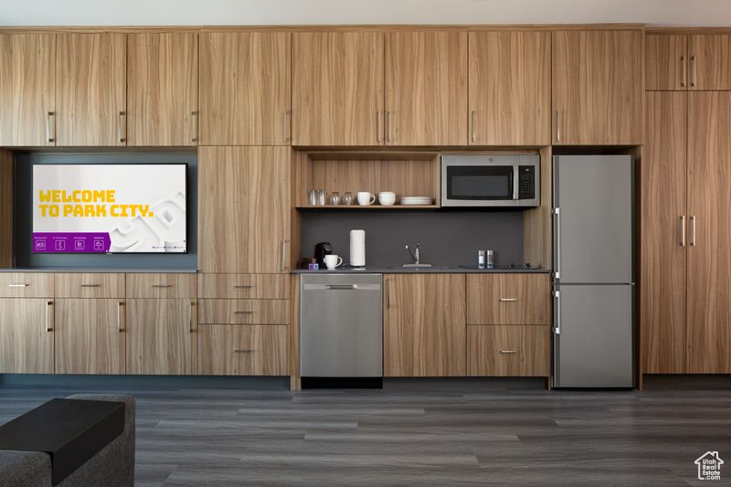 Kitchen featuring dark wood-type flooring, stainless steel appliances, and sink