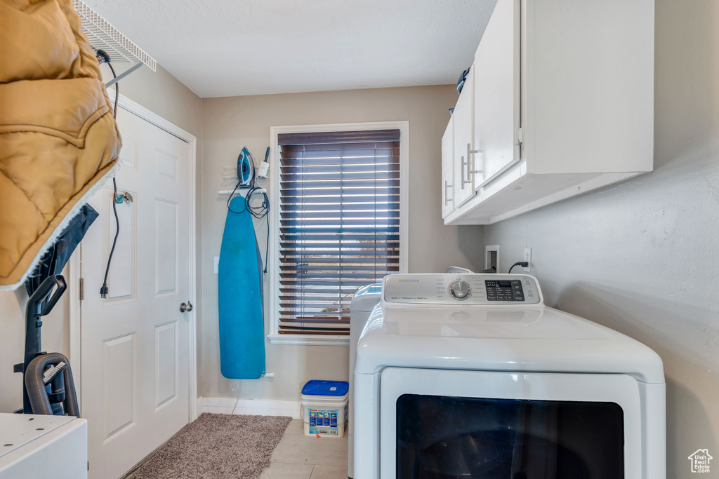 Laundry room with washer / dryer, cabinets, and light tile floors