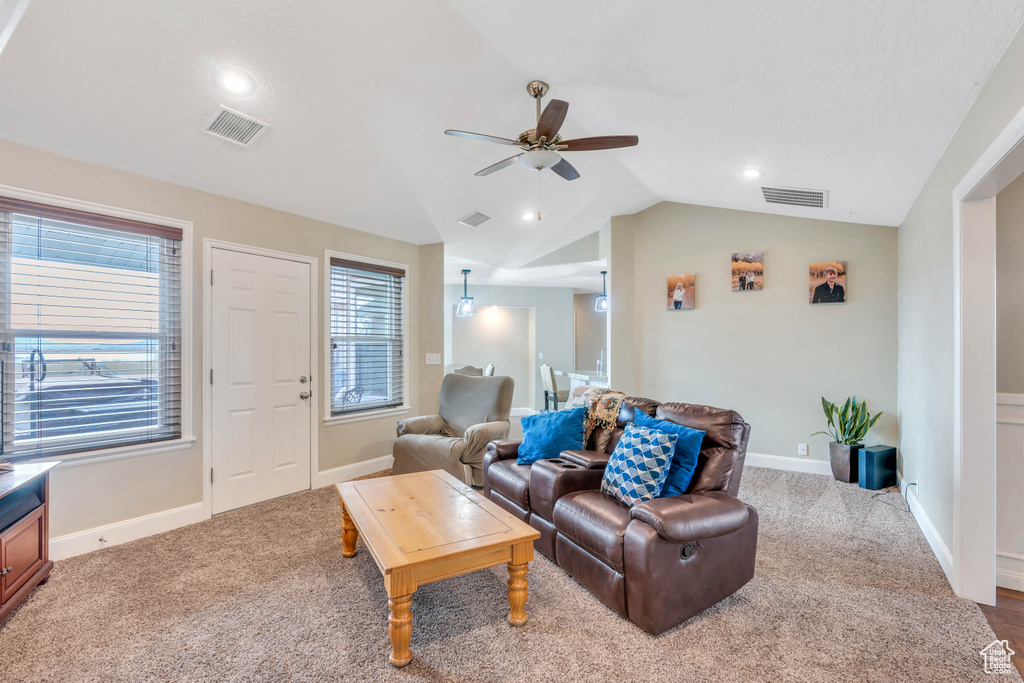 Carpeted living room featuring ceiling fan and lofted ceiling