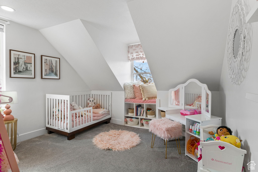 Carpeted bedroom with a crib and lofted ceiling