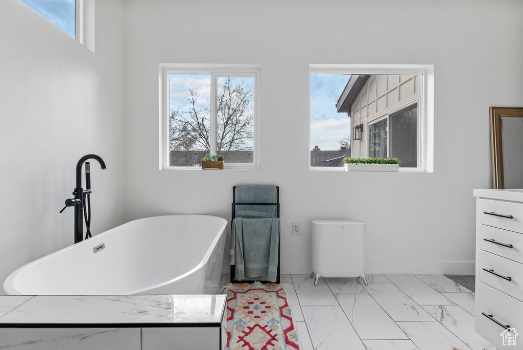 Bathroom featuring vanity, a tub, and tile flooring