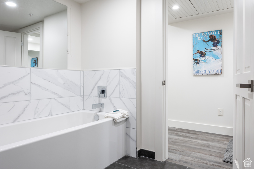 Bathroom with a bathtub, tile walls, and tile flooring