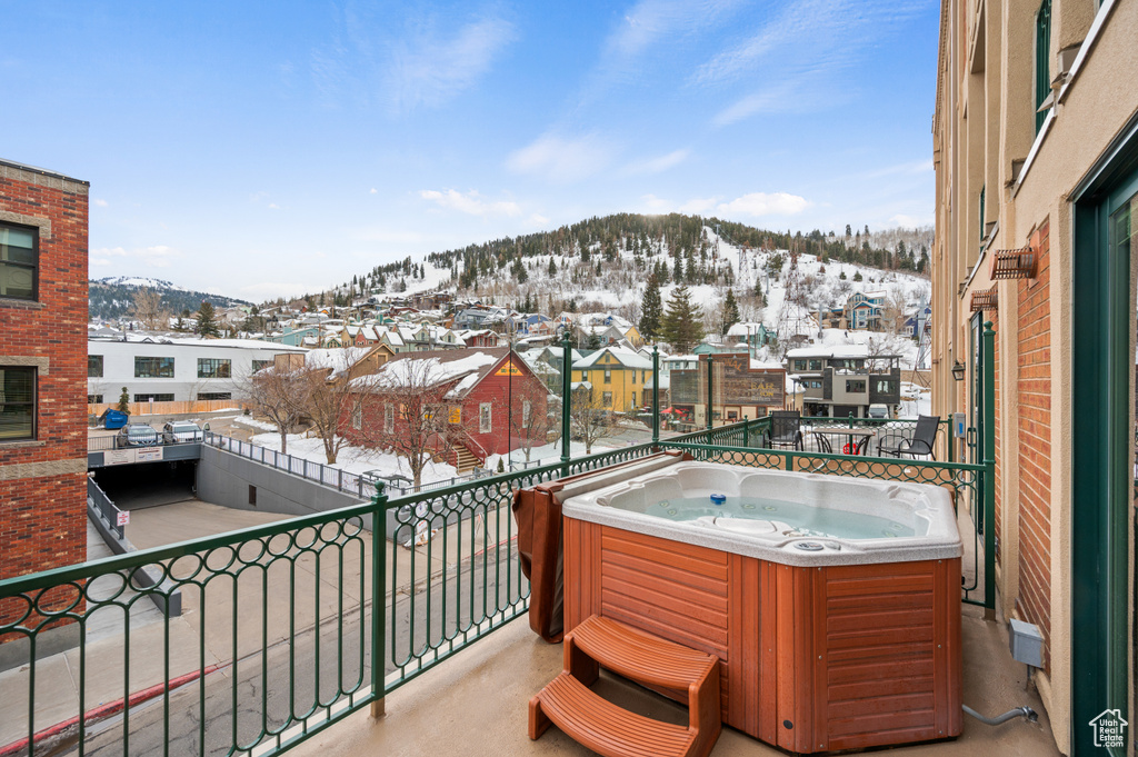 Snow covered back of property featuring a mountain view and a hot tub