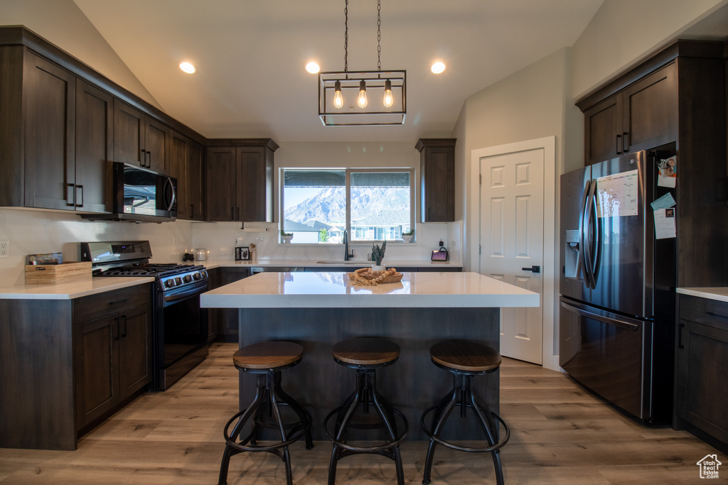 Kitchen with light hardwood / wood-style floors, black range with gas stovetop, a center island, and stainless steel fridge with ice dispenser