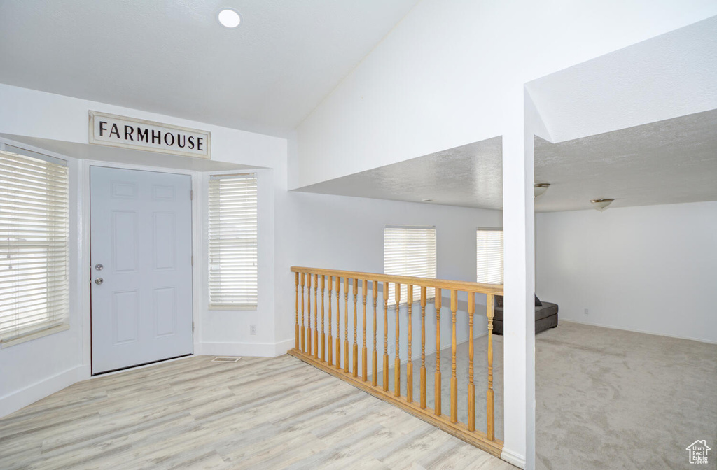 Foyer with light hardwood / wood-style floors and lofted ceiling