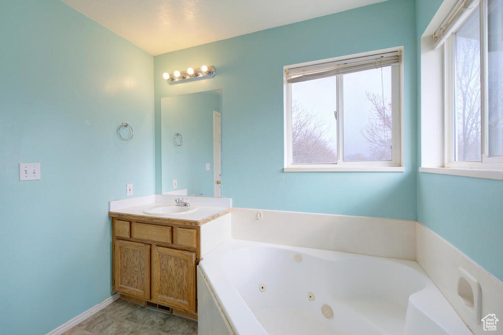 Bathroom featuring plenty of natural light, tile flooring, and vanity with extensive cabinet space
