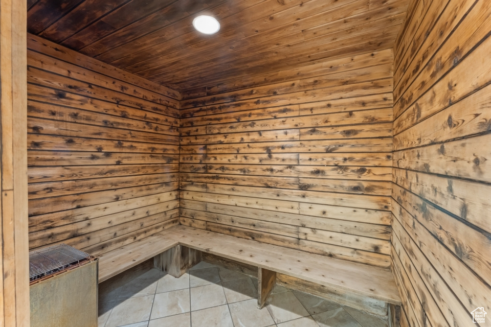 View of sauna with wood ceiling, wooden walls, and tile flooring