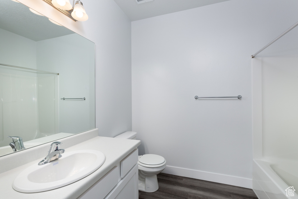 Full bathroom featuring hardwood / wood-style flooring, vanity, shower / tub combination, and toilet