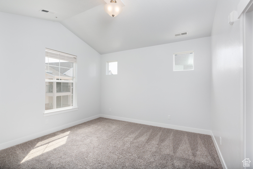 Spare room with vaulted ceiling and carpet flooring