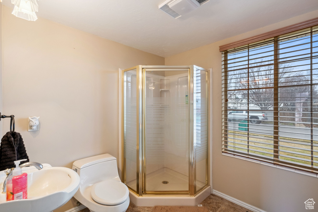 Bathroom featuring plenty of natural light, toilet, walk in shower, and sink