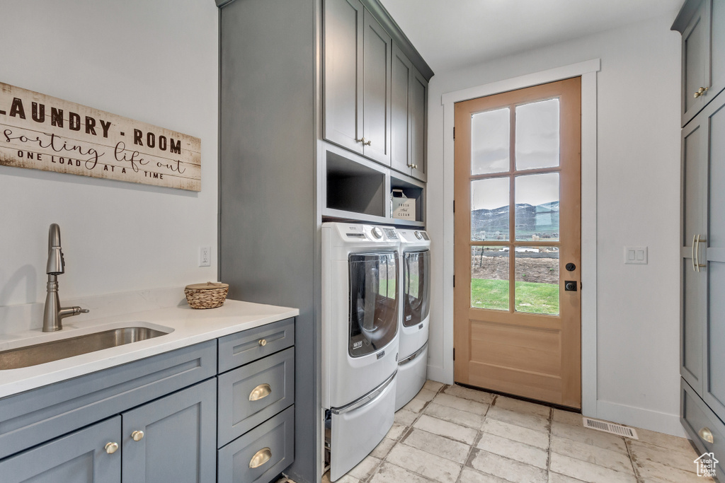 Clothes washing area with independent washer and dryer, cabinets, a mountain view, sink, and light tile floors