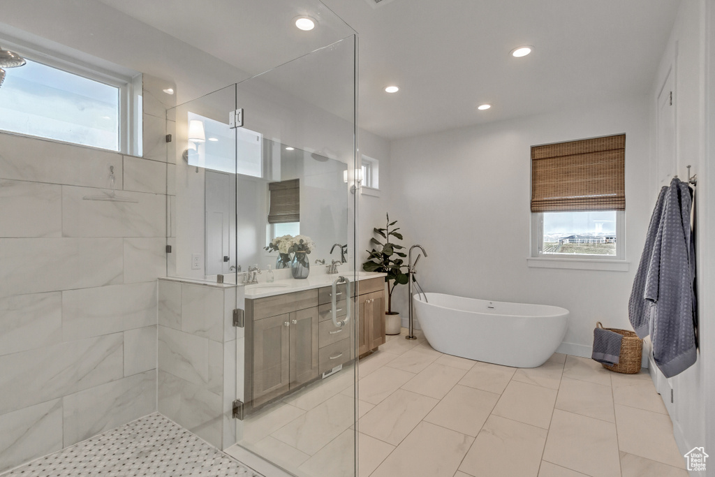 Bathroom featuring shower with separate bathtub, vanity with extensive cabinet space, and tile flooring