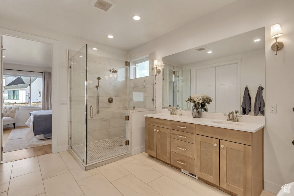 Bathroom featuring large vanity, walk in shower, double sink, and tile floors