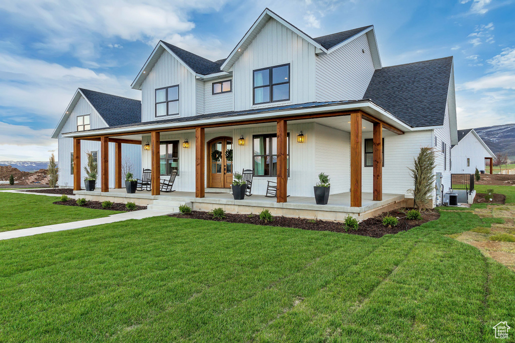 Modern inspired farmhouse featuring a front yard and covered porch