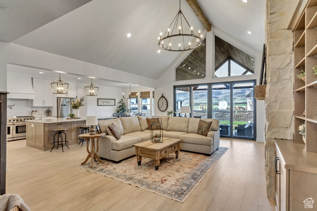 Living room with a chandelier, light hardwood / wood-style flooring, beam ceiling, and high vaulted ceiling