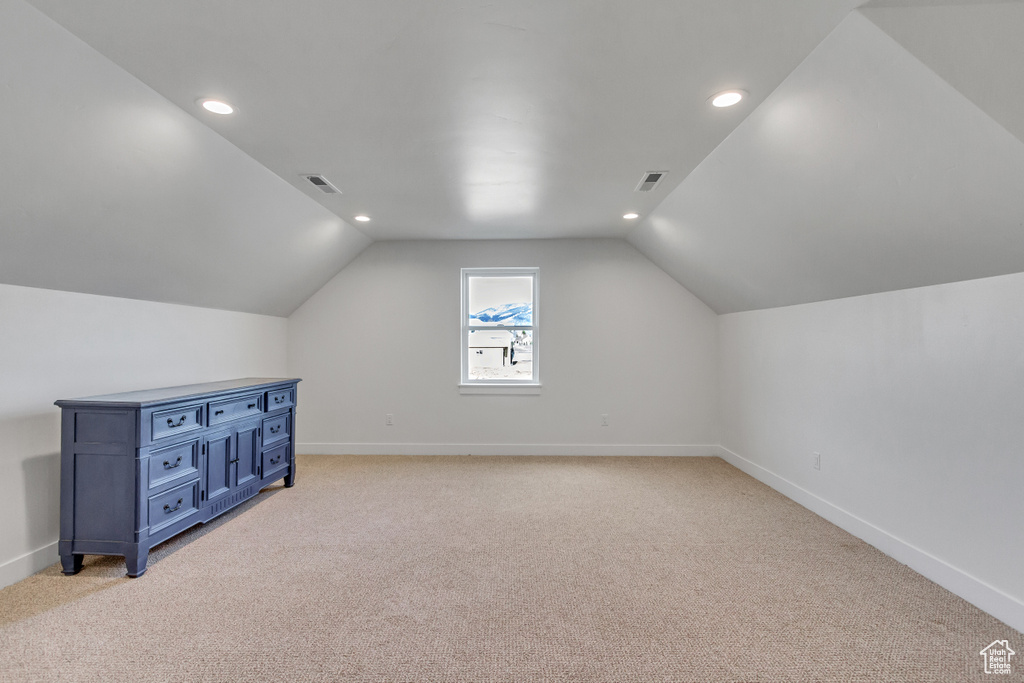 Bonus room with lofted ceiling and light carpet
