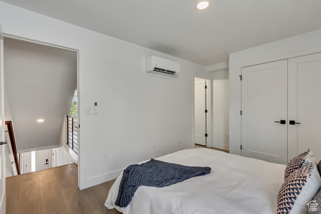 Bedroom with light hardwood / wood-style flooring, a wall mounted AC, and a closet