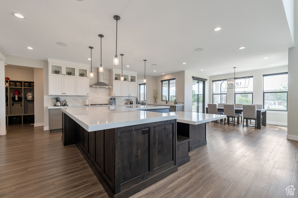 Kitchen with a chandelier, dark wood-type flooring, a center island, and pendant lighting