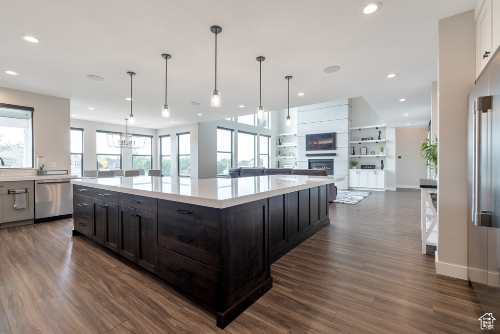 Kitchen with a center island, dark hardwood / wood-style flooring, decorative light fixtures, built in shelves, and dishwasher