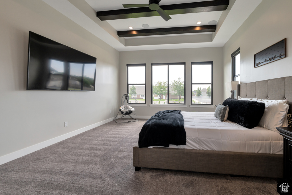 Bedroom with beam ceiling, ceiling fan, a raised ceiling, and carpet