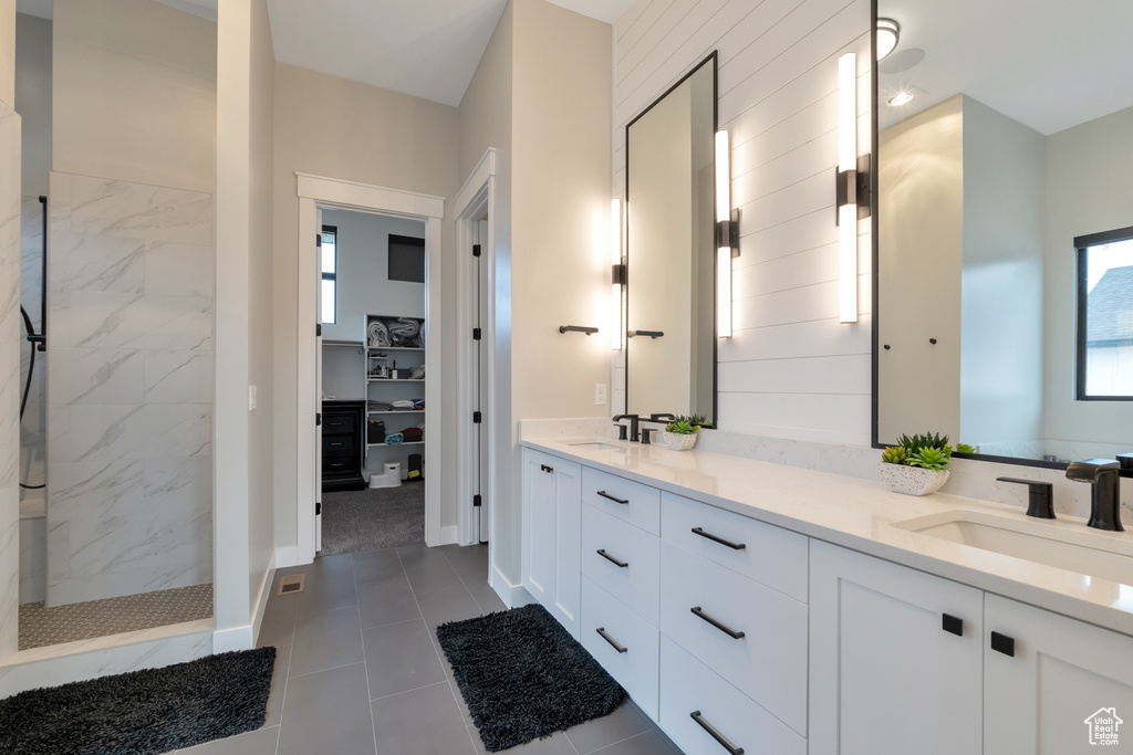Bathroom with tiled shower, tile floors, dual sinks, and vanity with extensive cabinet space