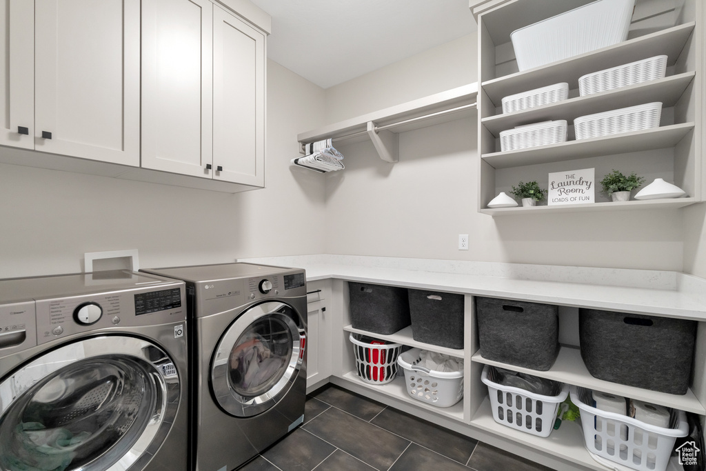Laundry area with washing machine and clothes dryer, hookup for a washing machine, dark tile flooring, and cabinets