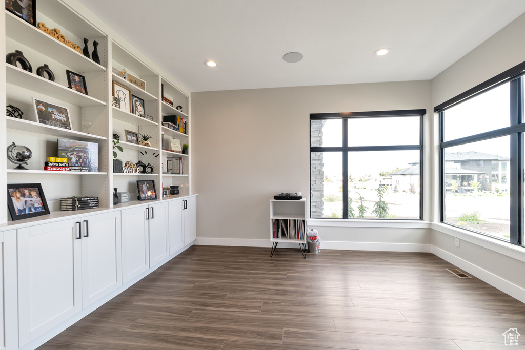 Unfurnished room with a wealth of natural light, built in shelves, and dark hardwood / wood-style floors